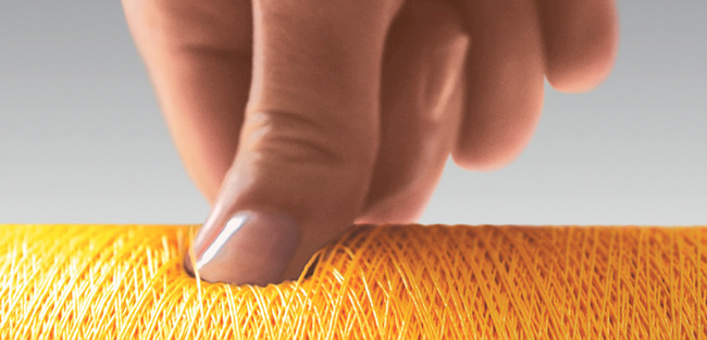Soft wounded spool Thumb pressing on a yellow spool to show how soft the spool ist wound